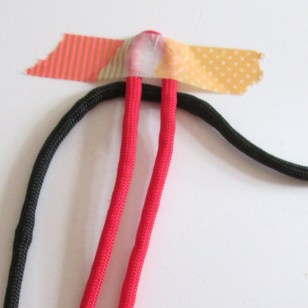 Cut 2 lengths of cord. Tape the middle of one to a board. Match the middle of the other one and place underneath.